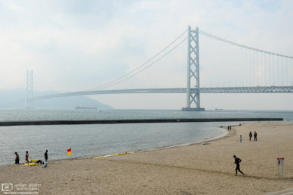 Beachside activities against the backdrop of Akashi Kaikyō, the beautiful suspension bridge in Kobe, Japan.