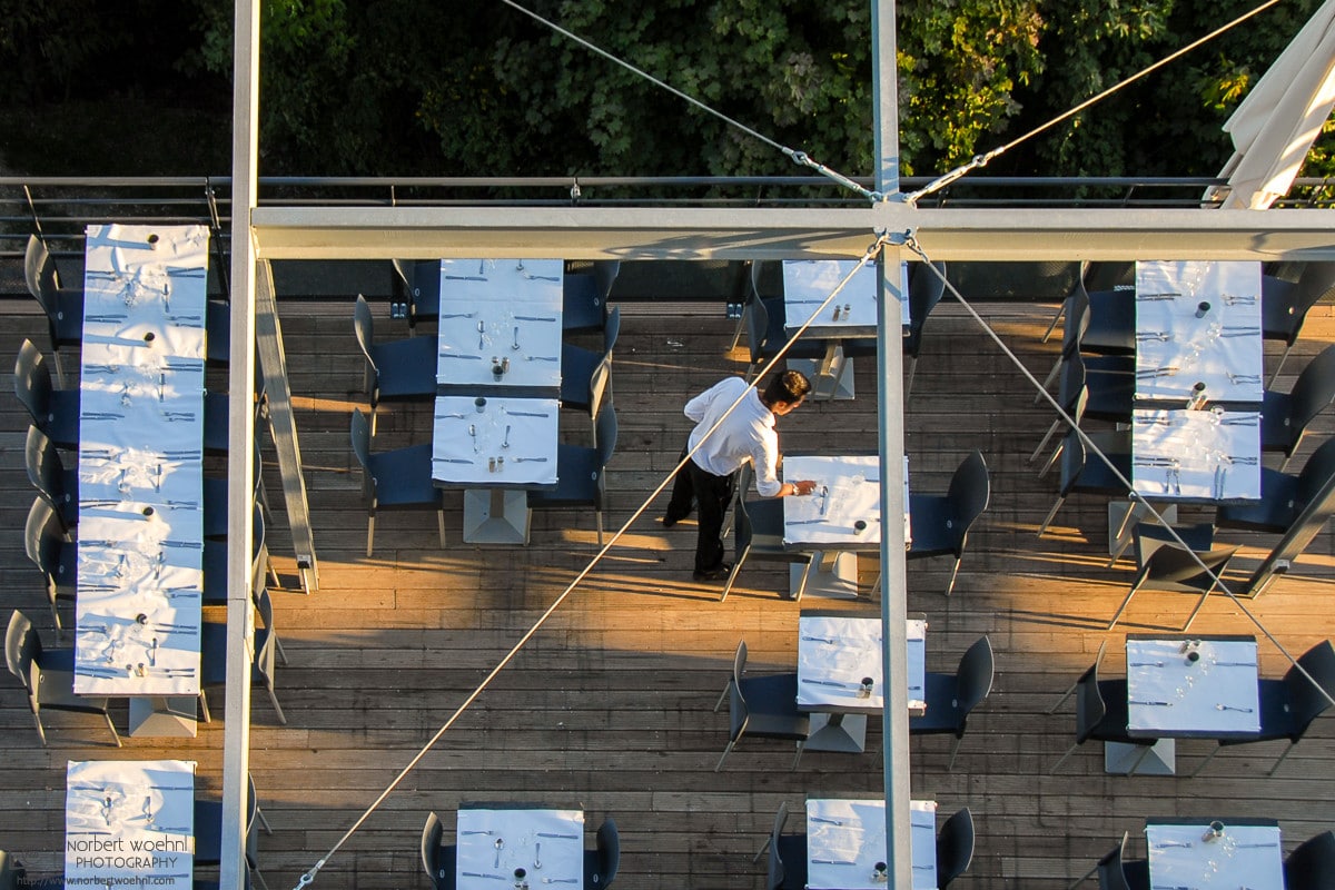 At a restaurant on La Bastille in Grenoble, France, tables are being set for the evening's guests.