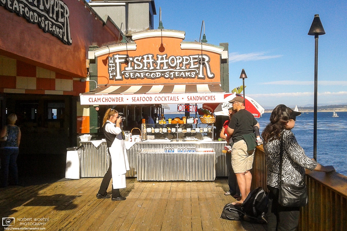 Staff are snapping a photo of a family outside an oceanside restaurant in Monterey, California.