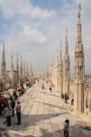 Tourists taking in the incredible views from the rooftop of Duomo di Milano, the cathedral church of Milan, Italy.