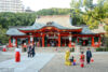 Visitors and shrine maiden are engaging in various activities outside the main hall of Ikuta Shrine in Kobe, Japan.