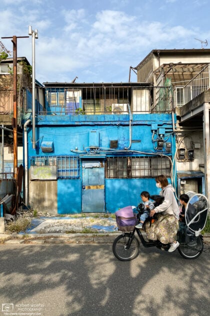 A fully occupied bicycle passes a colorful building in the Kirigaoka area of the Kita ward in Tokyo, Japan.