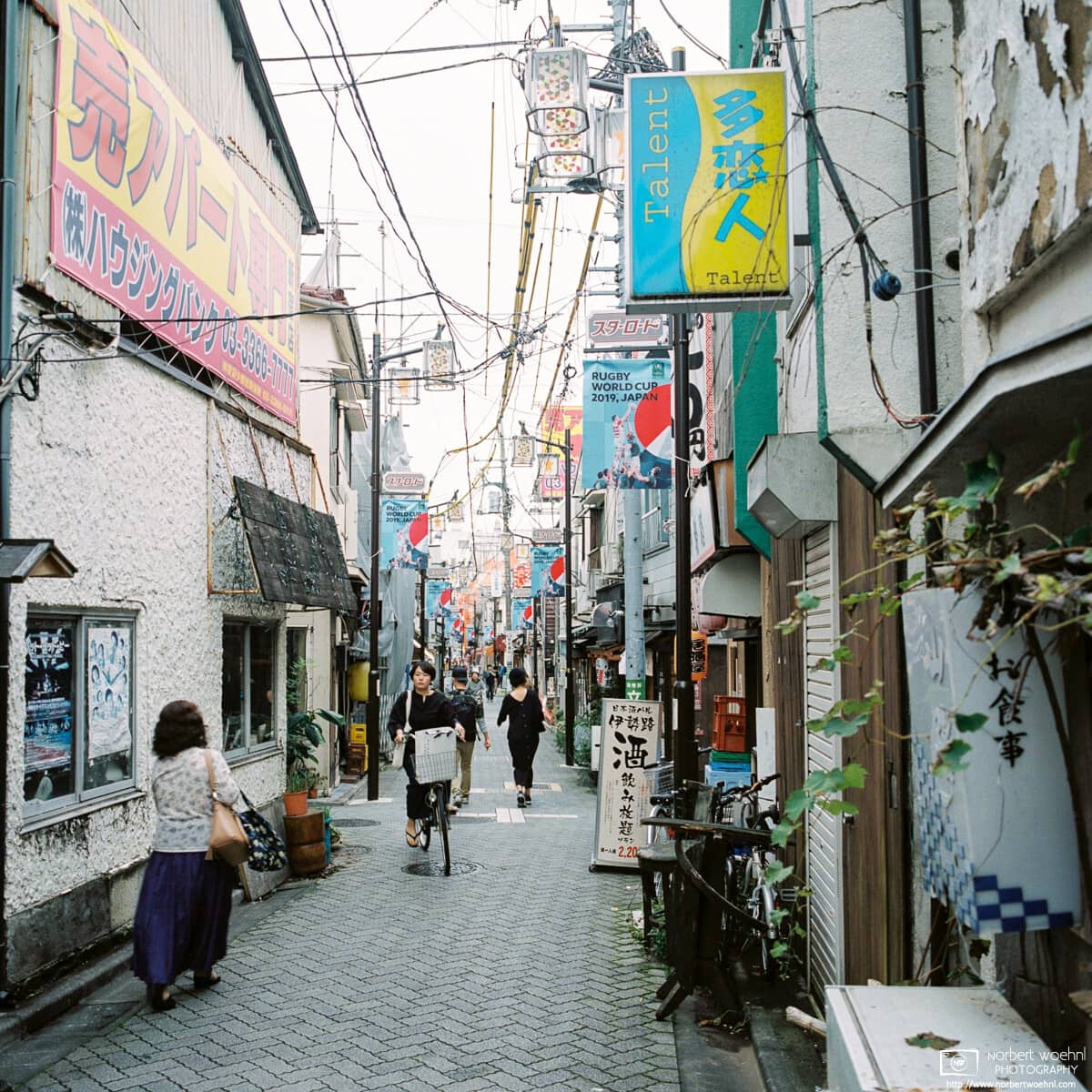 Pedestrian and bicycle traffic along Star Road, a pub-lined alley in Asagaya, Tokyo, Japan.