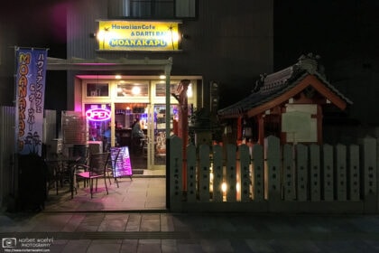 Nighttime view of a Hawaiian Cafe and Darts Bar in Nara, Japan, complete with an adjacent shrine.