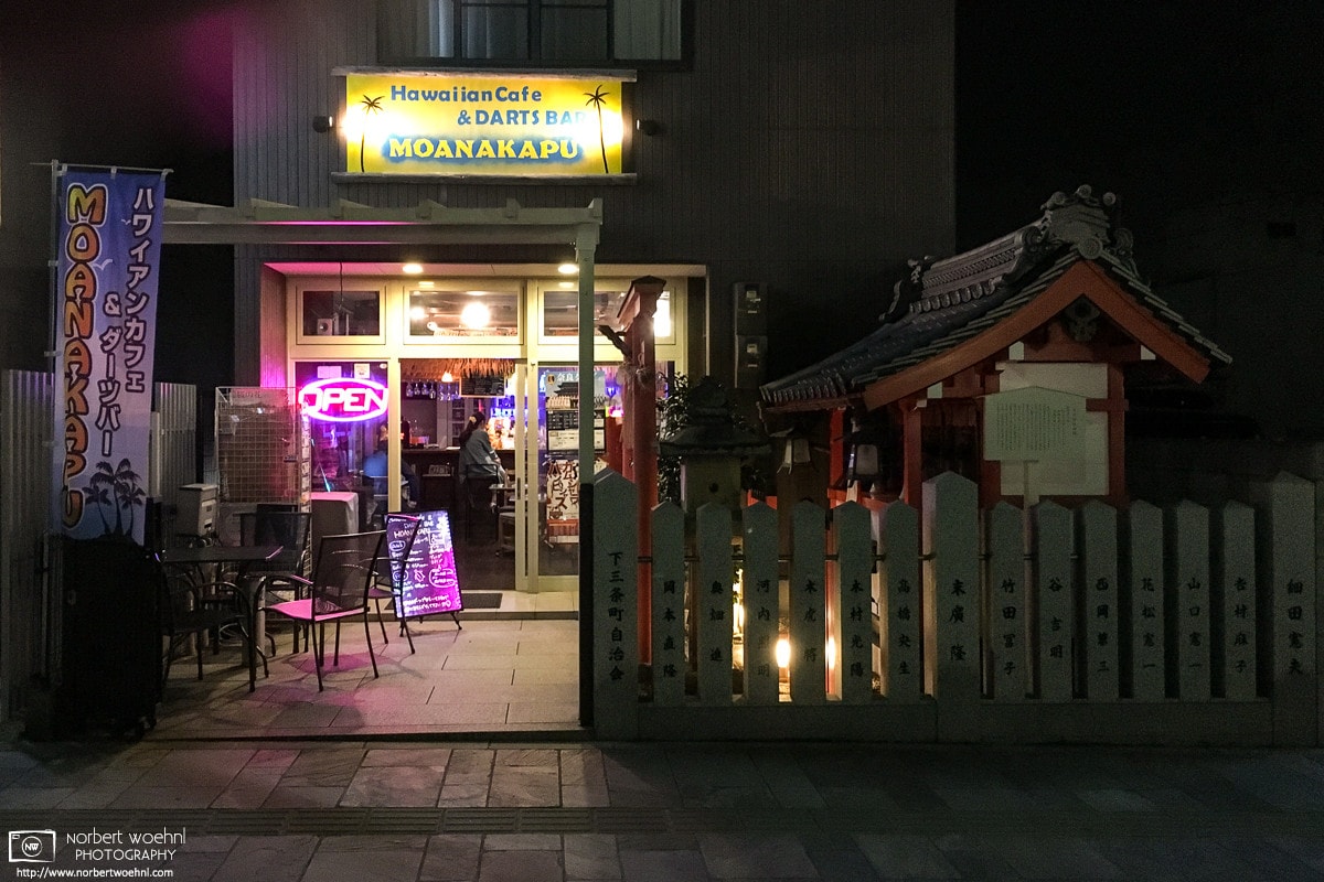 Nighttime view of a Hawaiian Cafe and Darts Bar in Nara, Japan, complete with an adjacent shrine.